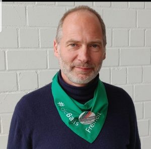 Werner Berends trägt ein grünes Halstuch mit dieBasis Aufschrift und "Freiheit"